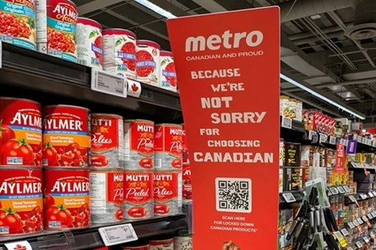 カナダのスーパーMetroの店頭。トマト缶の棚の横に、Because we're not sorry for choosing Canadianと書かれた赤いサイネージ